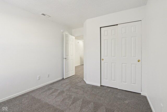 unfurnished bedroom featuring carpet, visible vents, baseboards, a closet, and a textured ceiling