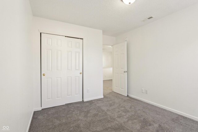 unfurnished bedroom featuring a closet, visible vents, baseboards, and carpet floors