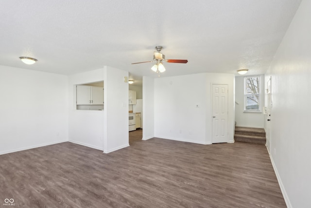 unfurnished living room featuring baseboards, stairs, dark wood-style floors, a textured ceiling, and a ceiling fan