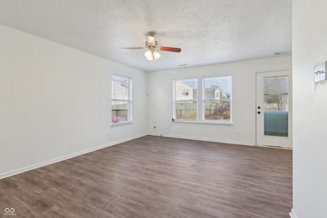 unfurnished room with visible vents, a textured ceiling, baseboards, and dark wood-style flooring