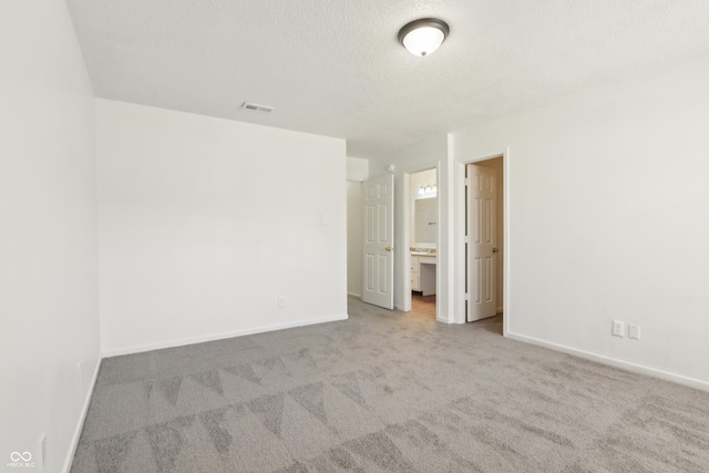 spare room featuring visible vents, baseboards, carpet, and a textured ceiling