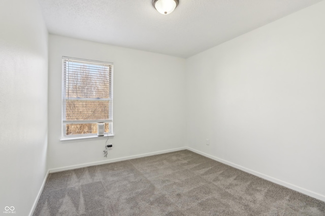 empty room with carpet flooring, baseboards, and a textured ceiling