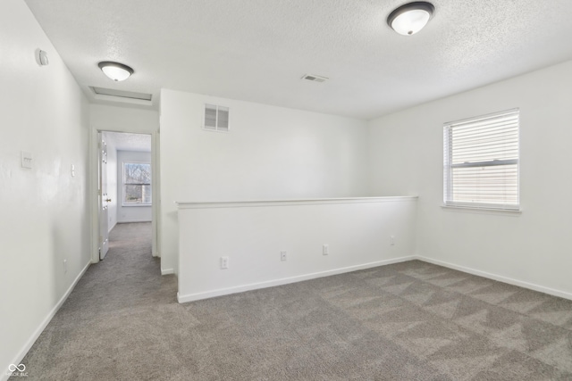unfurnished room with baseboards, carpet, visible vents, and a textured ceiling