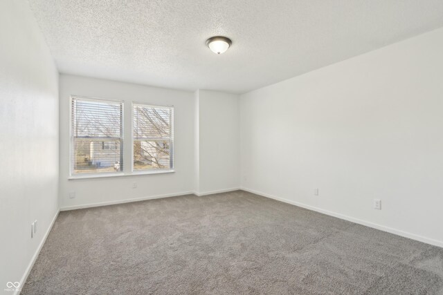 carpeted empty room featuring a textured ceiling and baseboards