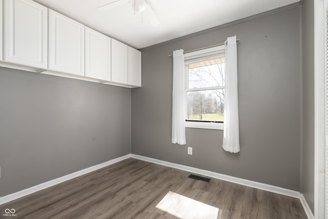 unfurnished room with a ceiling fan, visible vents, baseboards, and dark wood-style flooring