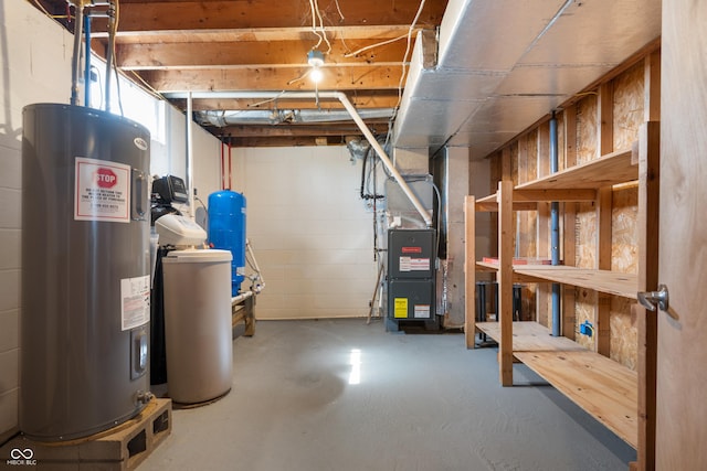 basement with concrete block wall, heating unit, and electric water heater