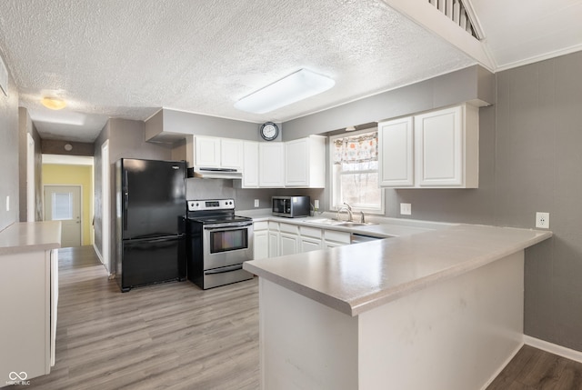 kitchen with under cabinet range hood, a sink, stainless steel appliances, light wood-style floors, and a peninsula