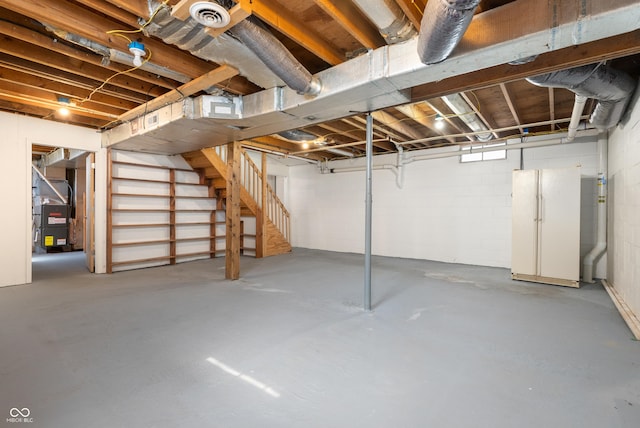 unfinished below grade area featuring visible vents, heating unit, and stairs