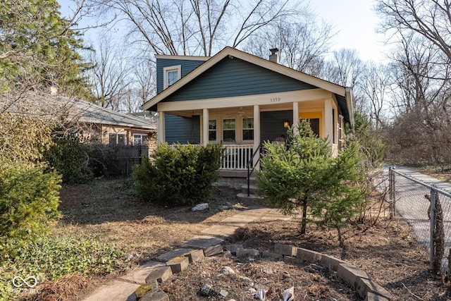 view of front of house with a porch, a chimney, and fence