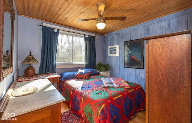 bedroom with a ceiling fan, wood finished floors, wooden walls, and wood ceiling