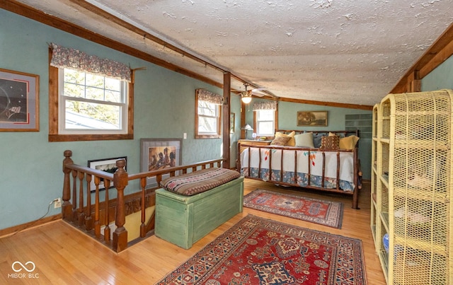 bedroom featuring a textured ceiling, wood finished floors, baseboards, and vaulted ceiling