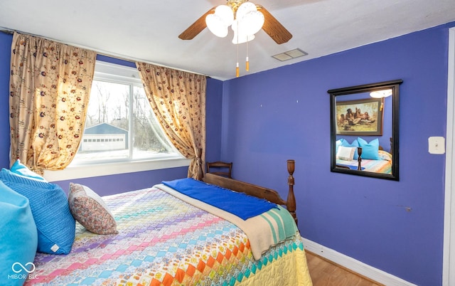 bedroom with visible vents, baseboards, wood finished floors, and a ceiling fan