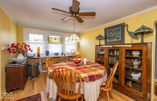 dining room with light wood-style flooring, ornamental molding, and a ceiling fan