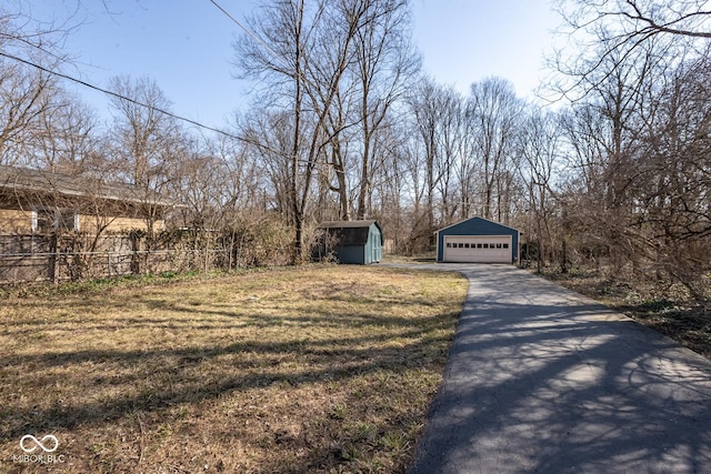 exterior space featuring fence, a yard, a garage, an outdoor structure, and a storage unit