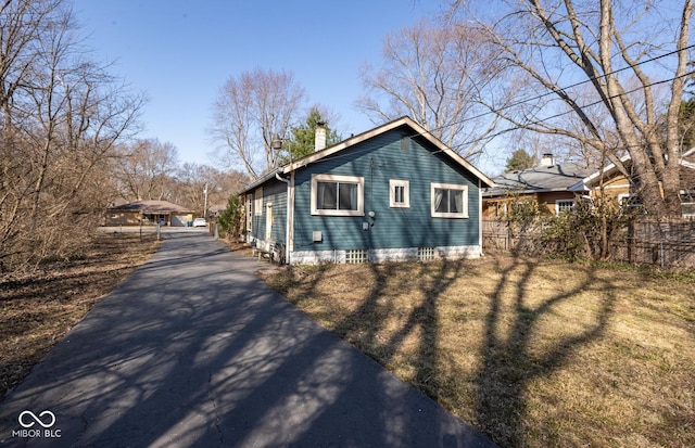 view of property exterior with a yard, fence, and a chimney