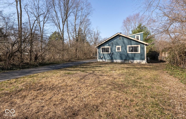 view of property exterior with aphalt driveway and a lawn