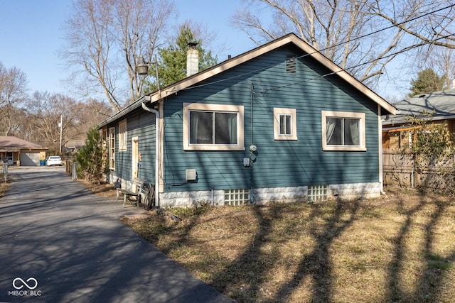 view of property exterior with a chimney and fence