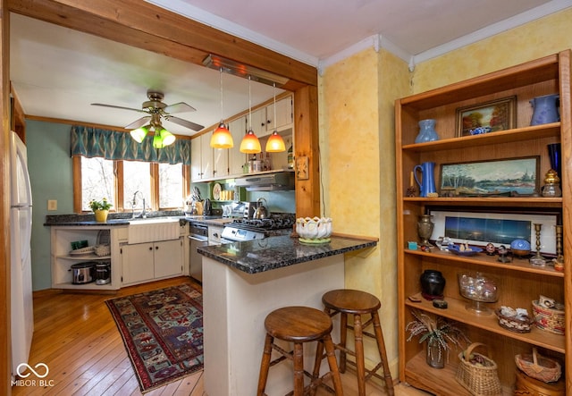 kitchen featuring light wood finished floors, open shelves, ornamental molding, under cabinet range hood, and range