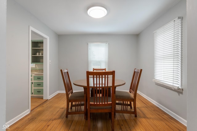 dining space with a wealth of natural light, baseboards, and light wood-style flooring