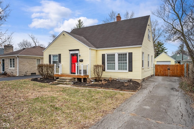 view of front facade with driveway, a front lawn, a gate, a shingled roof, and a chimney