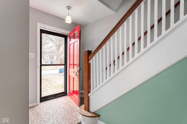 entrance foyer with plenty of natural light, stairs, and baseboards