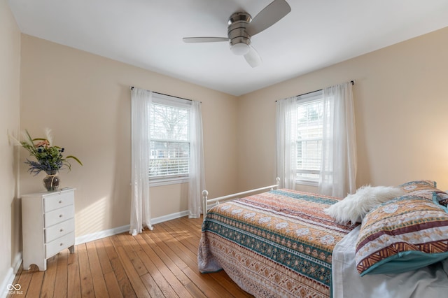 bedroom featuring multiple windows, light wood-type flooring, baseboards, and ceiling fan