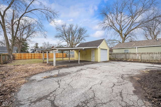 garage with a garage, driveway, and fence