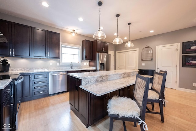 kitchen with stainless steel appliances, a kitchen breakfast bar, light wood-style flooring, and a center island