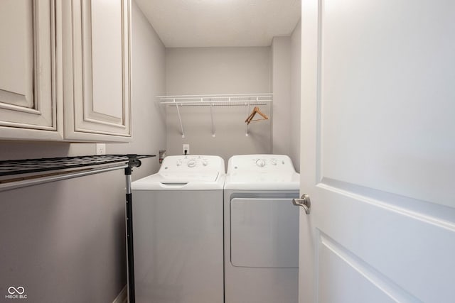 laundry area featuring cabinet space, a textured ceiling, and independent washer and dryer