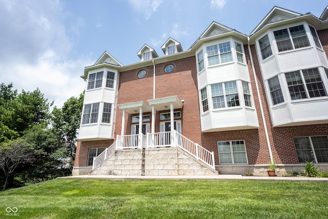 view of front of property featuring stairway, brick siding, and a front yard