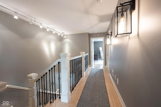 hall featuring baseboards, an upstairs landing, and light wood-style flooring