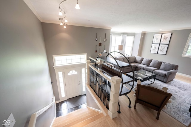 living room with a textured ceiling, wood finished floors, baseboards, and ornamental molding