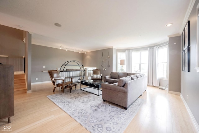 living area featuring light wood-style flooring, baseboards, ornamental molding, and stairs