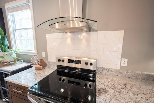 kitchen featuring light stone counters, stainless steel electric stove, ventilation hood, and decorative backsplash