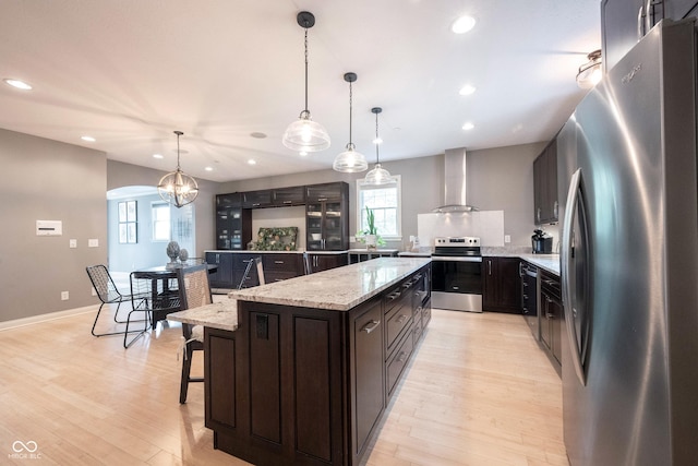 kitchen featuring wall chimney exhaust hood, light wood-style floors, plenty of natural light, and appliances with stainless steel finishes