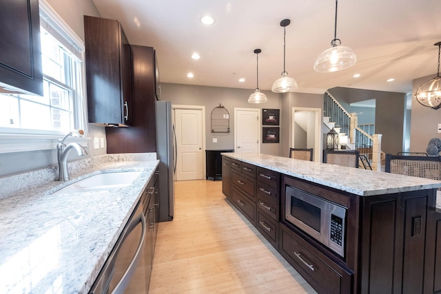 kitchen featuring light wood-type flooring, a sink, a kitchen island, recessed lighting, and appliances with stainless steel finishes