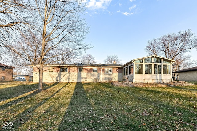 view of front of property featuring brick siding, a chimney, a front lawn, and a sunroom