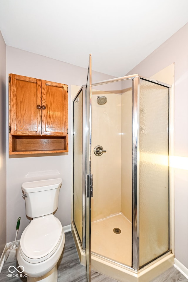 full bathroom with a shower stall, toilet, baseboards, and wood finished floors