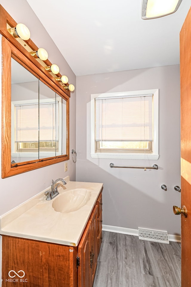 bathroom with visible vents, vanity, baseboards, and wood finished floors