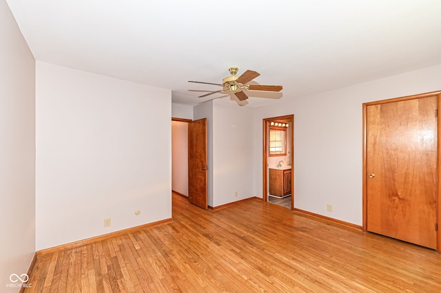 unfurnished bedroom with light wood-style flooring, a ceiling fan, ensuite bathroom, and baseboards