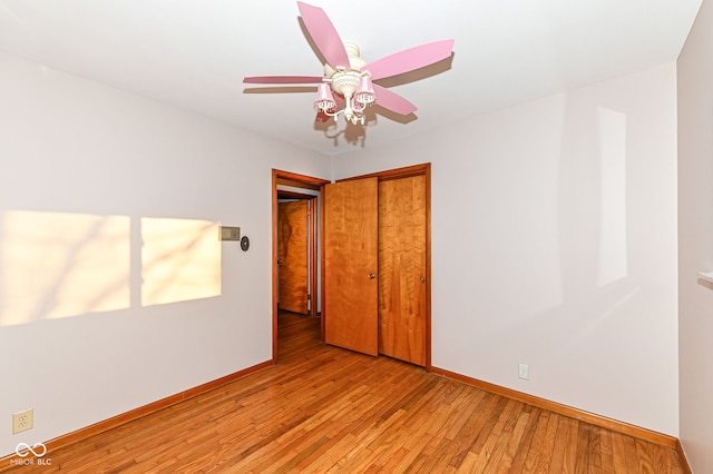 unfurnished bedroom featuring a closet, light wood-style flooring, a ceiling fan, and baseboards