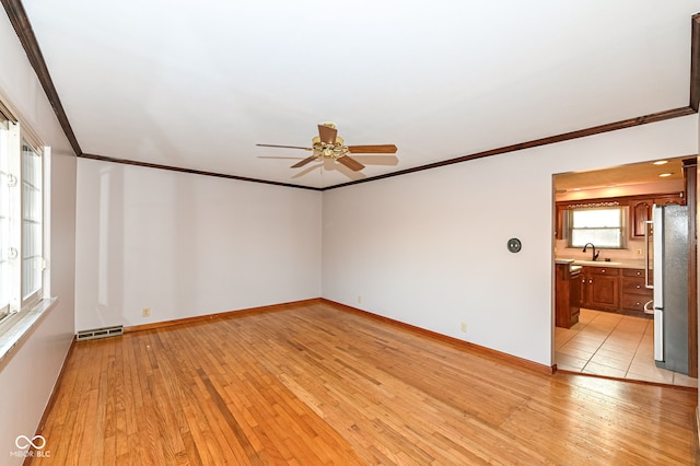 spare room with visible vents, ceiling fan, a sink, crown molding, and light wood-type flooring