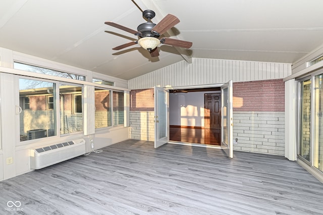 unfurnished sunroom featuring lofted ceiling with beams, a ceiling fan, and a wall unit AC