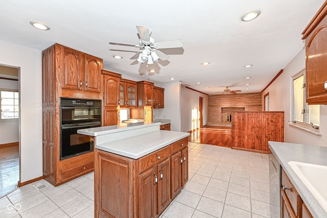 kitchen with brown cabinetry, dobule oven black, light countertops, and a ceiling fan