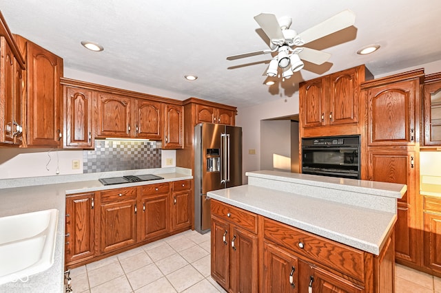 kitchen featuring backsplash, light countertops, brown cabinetry, black appliances, and a sink