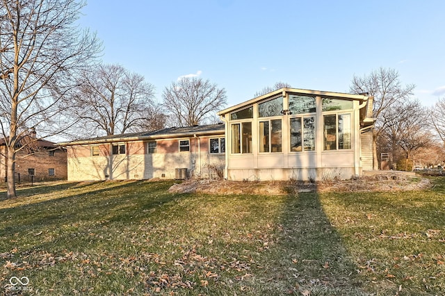 rear view of house featuring a yard and a sunroom