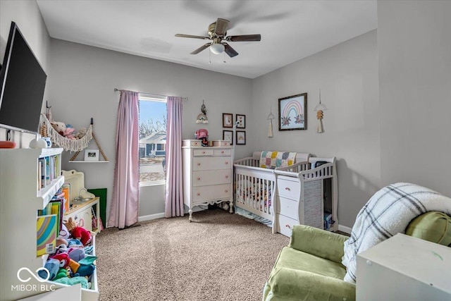 bedroom with baseboards, carpet floors, a nursery area, and ceiling fan