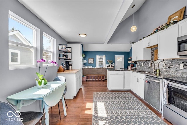 kitchen featuring backsplash, wood finished floors, appliances with stainless steel finishes, white cabinets, and a peninsula