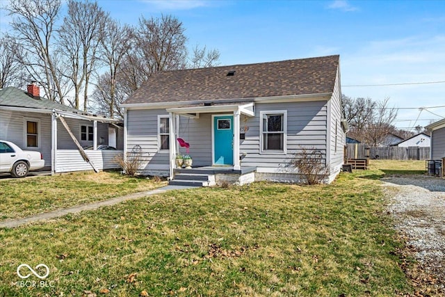 bungalow with a front lawn, fence, and a shingled roof