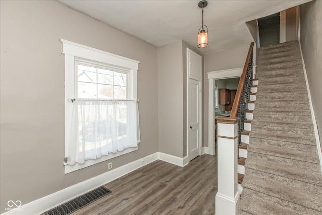 staircase with wood finished floors, visible vents, and baseboards